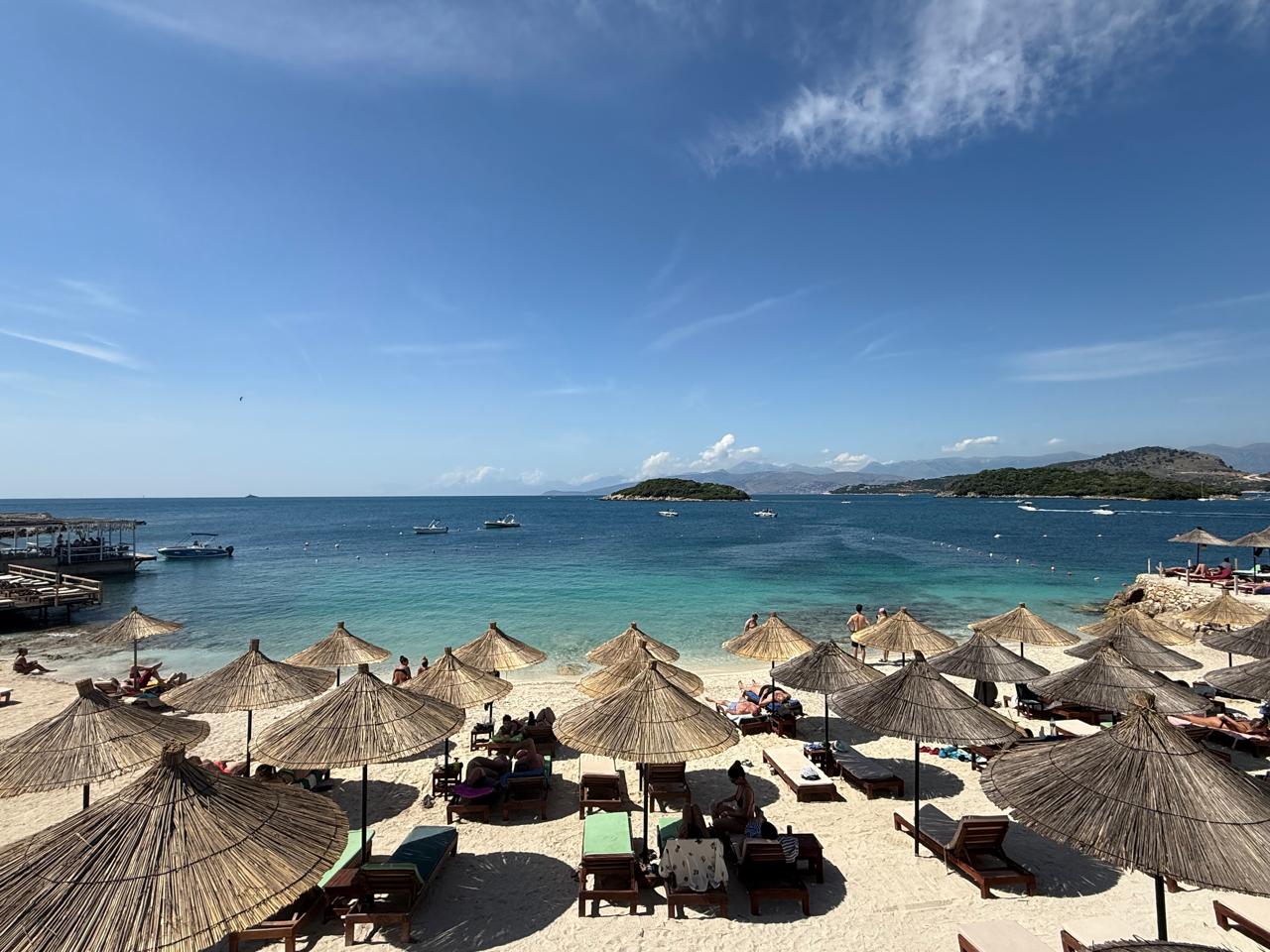 Reed umbrellas and sunbeds on the Ksamil beach in front of Summer Gate
